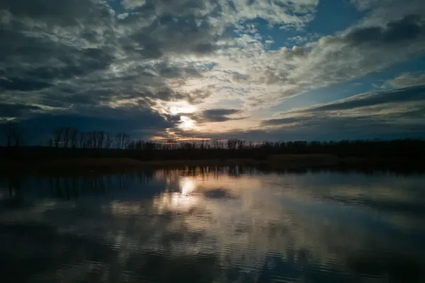 Dramatic sunset over the water at Begečka Jama near Novi Sad, showcasing clouds and reflections.