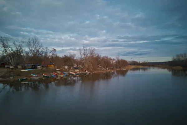 Boats resting on the serene shore of Begečka Jama, Novi Sad, Serbia, under a dramatic, cloudy sky.