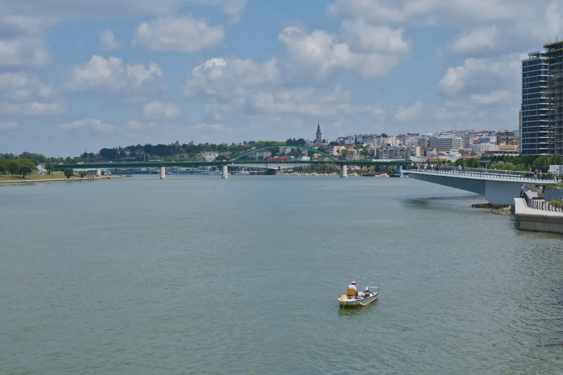 Un pescador solitario en un bote en el río Sava, con vistas a los puentes y al paisaje urbano de Belgrado.