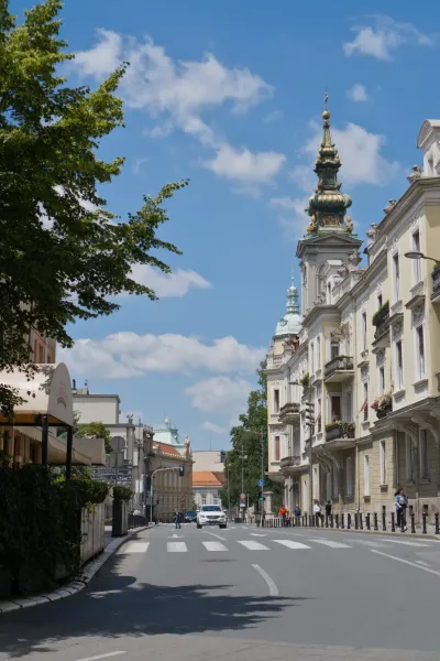 Belgrade street with Baroque architecture and an Orthodox cathedral under a clear sky.