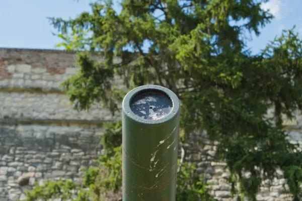 Open-air museum in Kalemegdan, Belgrade: green cannon against a stone wall and trees.