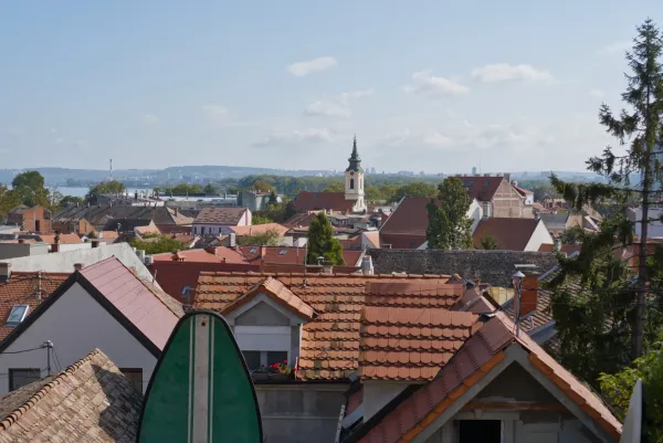Panoramic view of the Zemun district in Belgrade, Serbia, with numerous tile rooftops and a church in the distance.