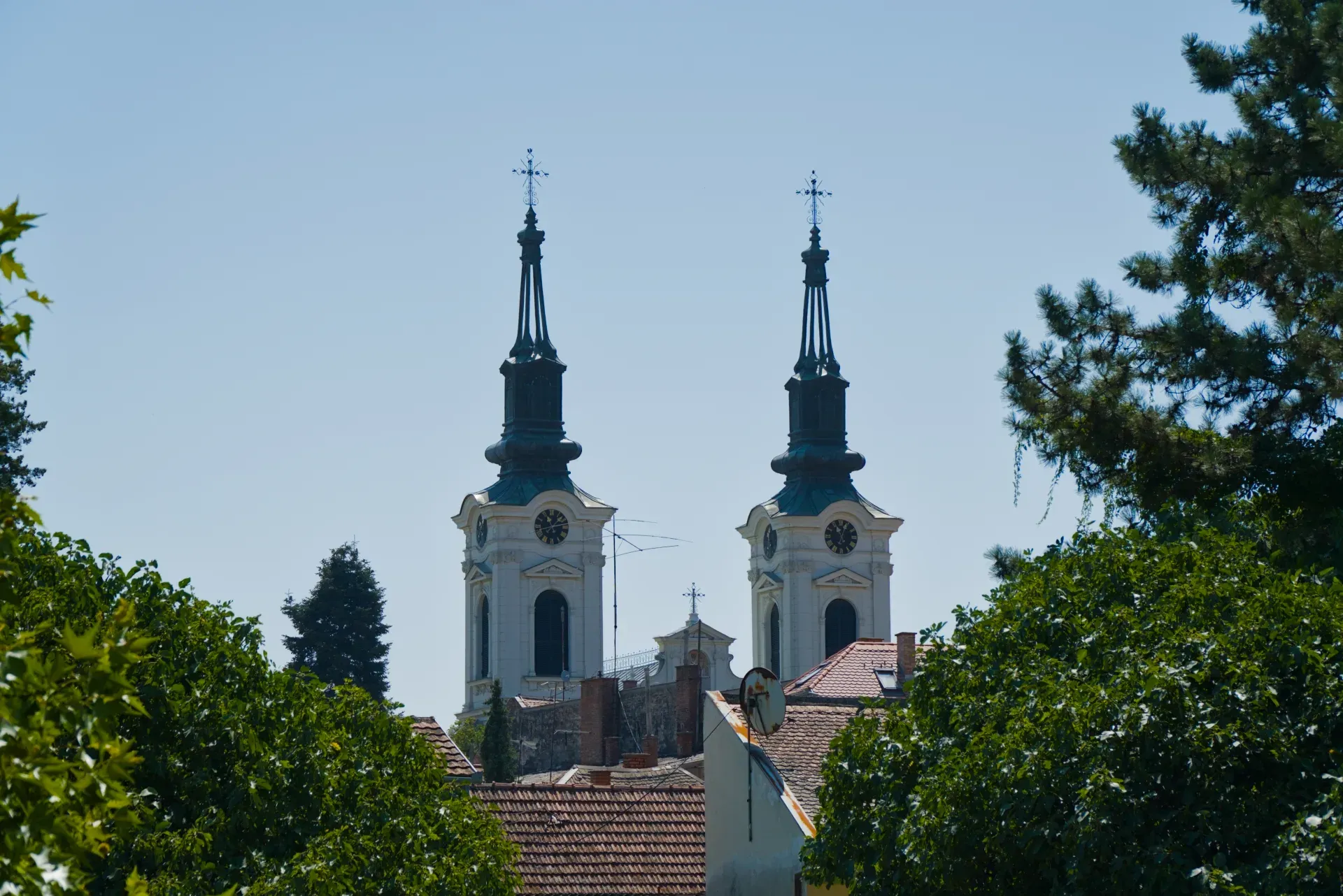Dva zvonika Crkve Svetog Nikole u Sremskim Karlovcima, Srbija, na pozadini vedrog plavog neba.