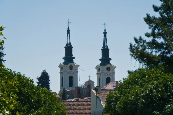 Two bell towers of Saint Nicholas Church in Sremski Karlovci, Serbia, against a clear blue sky.