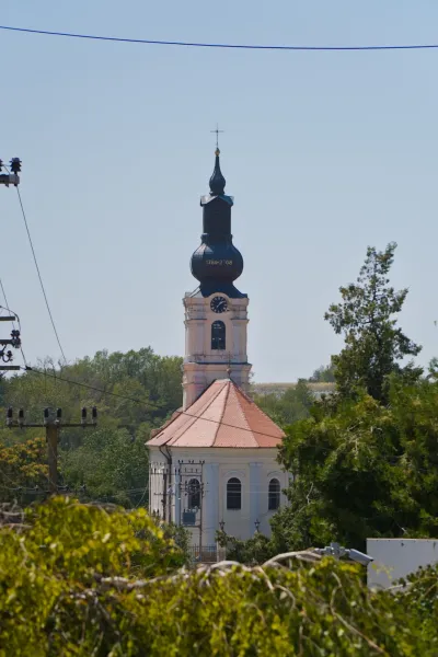 Portrait photograph of a church in Irig, Serbia, featuring a distinctive tower and roof, set against a clear blue sky.