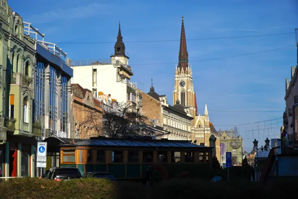 View of Liberty Square from Željeznička Street in Novi Sad, Serbia, with a tram and a church.