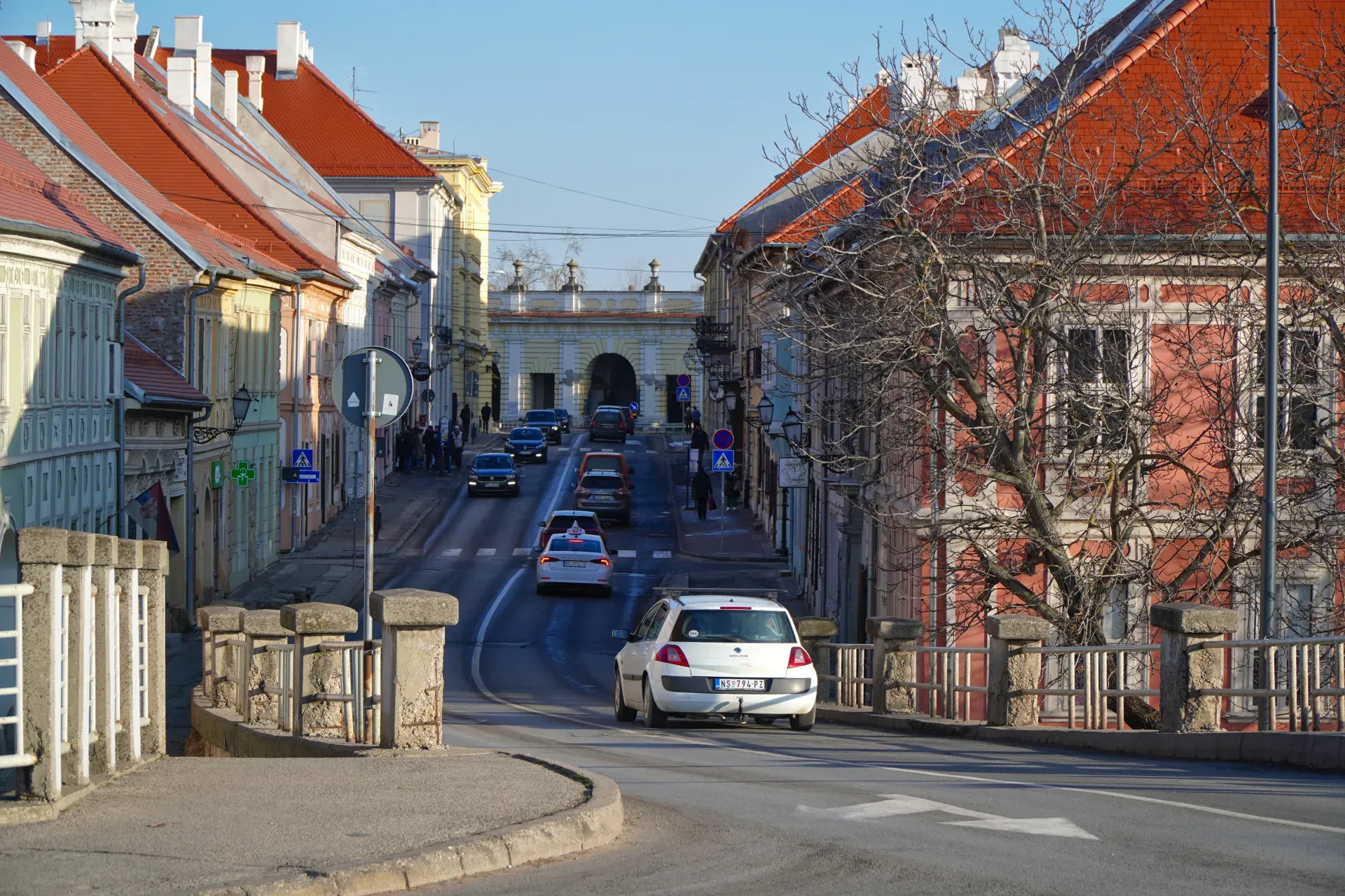 Calle colorida en Petrovaradin, Serbia, con edificios brillantes y coches.