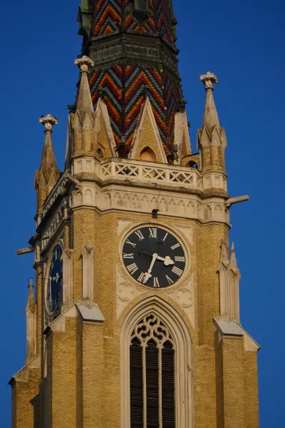 Close-up of the clock on the tower of the Church of the Virgin Mary in Novi Sad, Serbia, with Roman numerals on a dark dial.