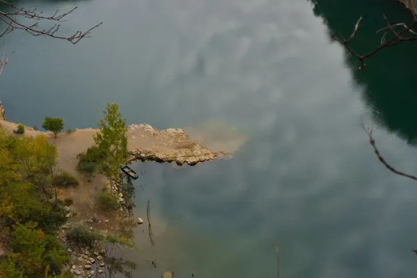 Boat on the shore of Ledinačko Lake, reflecting the cloudy morning sky.