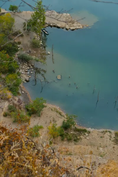A boat is moored to the shore of Lake Ledinačko with clear water, taken from above.