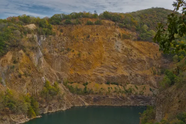 Steep cliffs and quarry around Ledinačko lake, Serbia, with ochre tones and green vegetation.