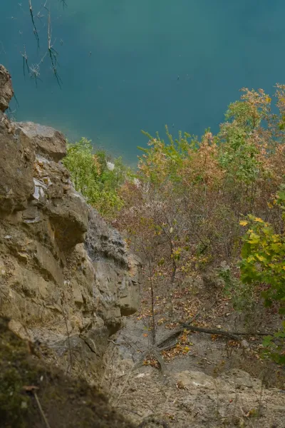 View from a high steep cliff to Ledinačko Lake, Serbia, with turquoise water and autumn trees.