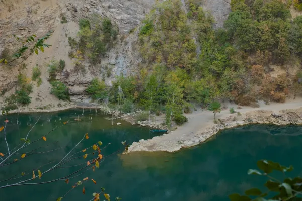 Small boat by the rocky shore of Ledinačko Lake, surrounded by trees and rocks.