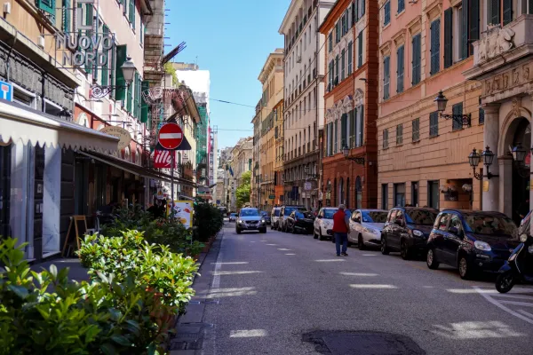 Vista della strada di Via Balbi a Genova Italia con edifici storici e auto parcheggiate sotto un cielo blu.