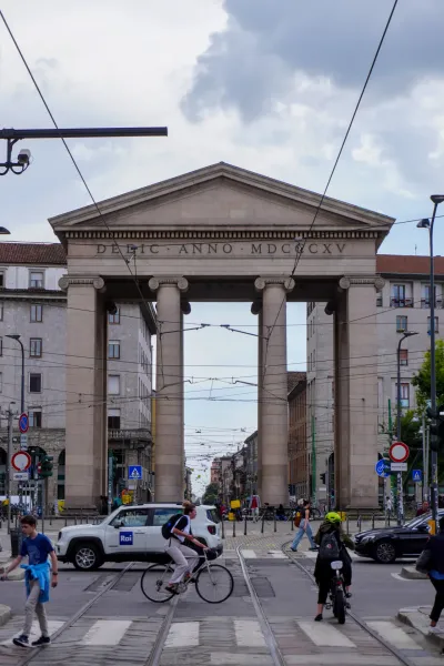 Vista di una strada acciottolata a Milano, Italia, fiancheggiata da edifici colorati con balconi in ferro battuto e persiane chiuse.
