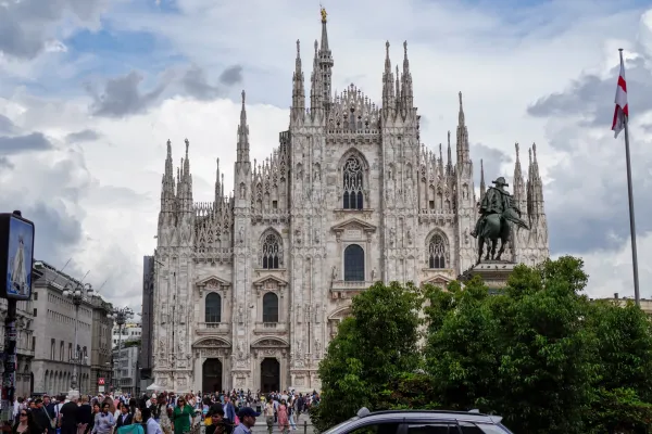 Eine Totale der Piazza Duomo in Mailand, Italien, mit dem ikonischen Mailänder Dom im Hintergrund und vielen Menschen, die durch den Platz gehen.